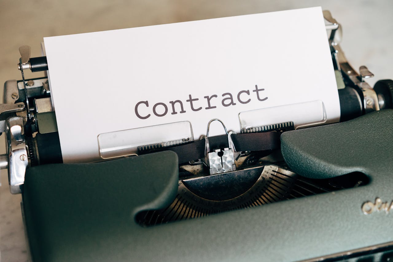 A close-up of a vintage typewriter with a typed contract page.